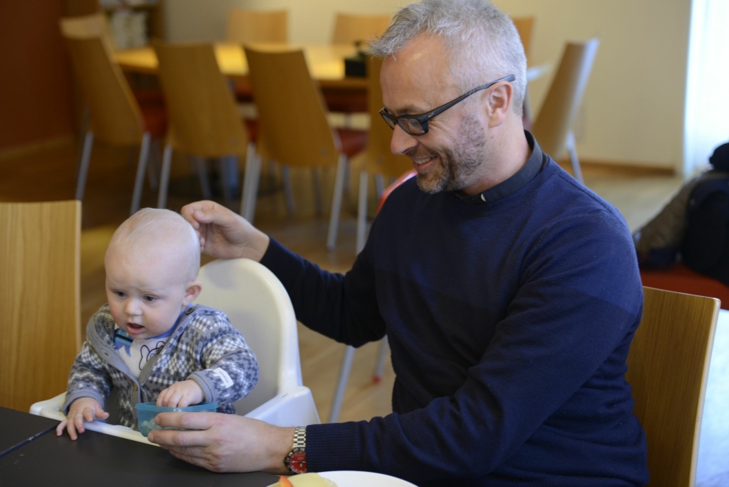 TILSTEDE: Anders Johansen hjelper Ebbe (9 mnd) med å få i seg lunsjen. Soknepresten spiser alltid lunsj med foreldre og barn etter babysangen.