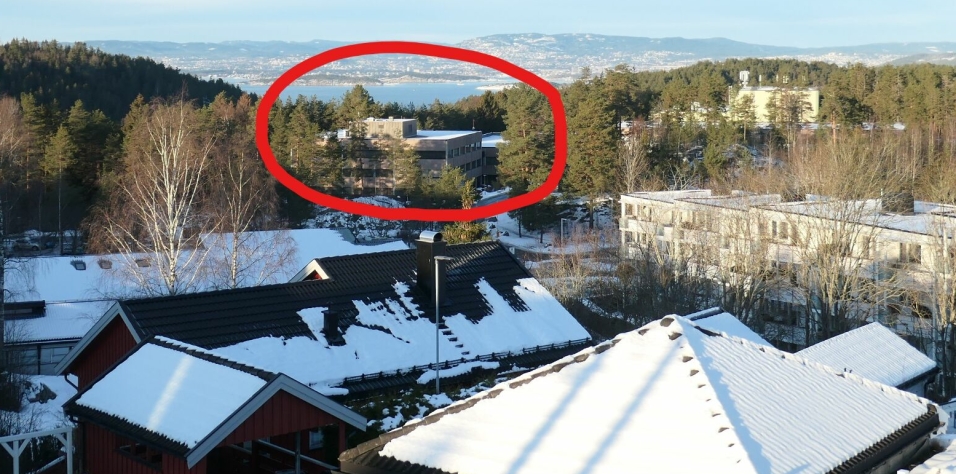 TETT PÅ BEBYGGELSE: Bildet viser den aktuelle tomten i Trollåsveien 8 (omringet i rødt) med den eksisterende næringsbebyggelsen, sett sett fra nabolaget rett ovenfor veien.